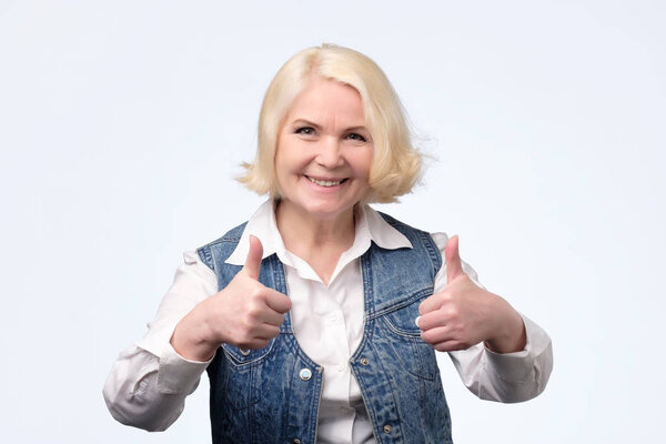 Elderly blonde european woman giving a thumb up
