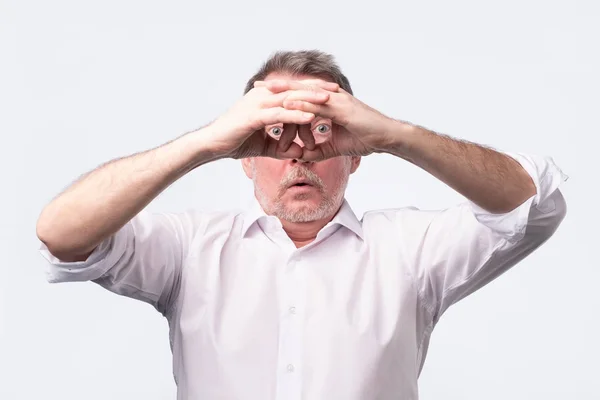 Senior man houdt zijn handen op zijn ogen als kijken door de verrekijker — Stockfoto