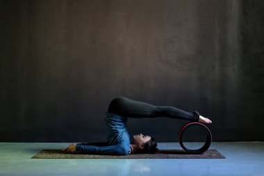 Girl in halasana pose doing yoga on black background. clipart