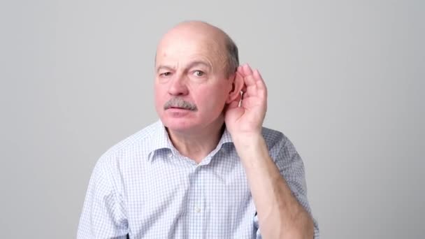 Senior Bald Man luisteren naar roddels over andere met de hand in de buurt van oor. — Stockvideo