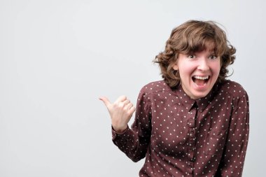 Gülümseyen genç kadın parmağını uzağa gösteriyor. Stüdyo çekimi