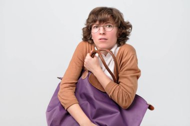 Gözlüklü genç bir kadın büyük bir çanta tutuyor..