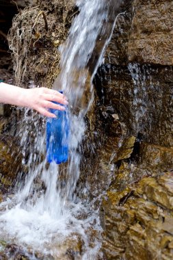 Plastik şişe tutan kadın soğuk pınardan temiz su çekiyor..