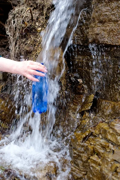 Mulher segurando uma garrafa de plástico tirando água limpa da fonte fria . — Fotografia de Stock