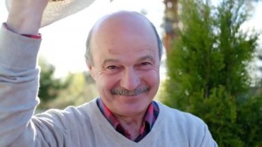 Dost canlısı yaşlı adam şapka koyar arkadaşlar ağırlıyor.
