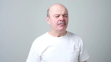 Yüzünde tiksinti ile Kıdemli İspanyol adam, burnunu çimdikleme