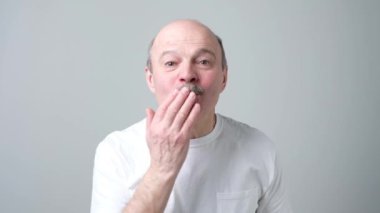 Beyaz t-shirt kıdemli adam hava öpüşme göndermek.