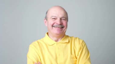 Kameraya bakarak gülen olgun yetişkin adam. Olumlu duygu kavramı