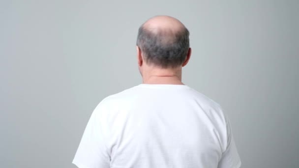 Senior man staat met zijn rug naar de camera en draait op zoek geïrriteerd — Stockvideo
