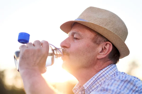 Sénior hispânico homem no verão hatdrinking água doce — Fotografia de Stock