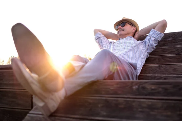 古いヒスパニックの男は、夏の晴れた日を楽しんで、笑顔でベンチに座っています. — ストック写真