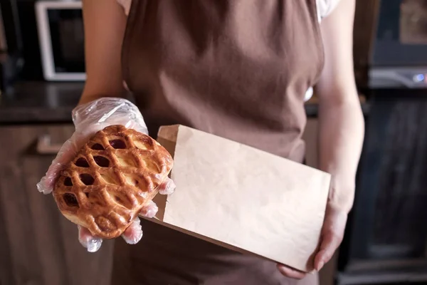 Woman putting sweet pie in paper bag — Stock Photo, Image