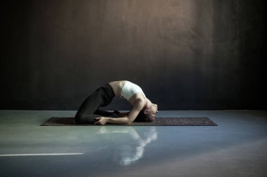Kadın yoga yapıyor, güvercin egzersizi yapıyor, Kapotasana pozu veriyor..