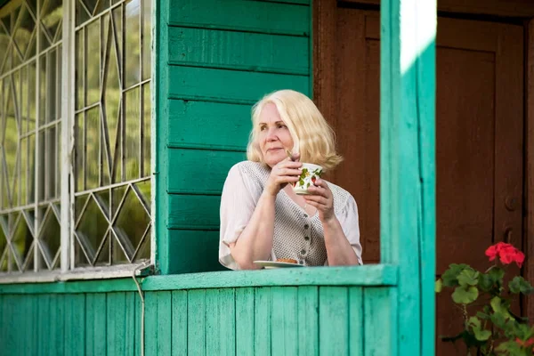Yaşlı kadın dinlenme ve yazlık terasta oturan çay içme — Stok fotoğraf