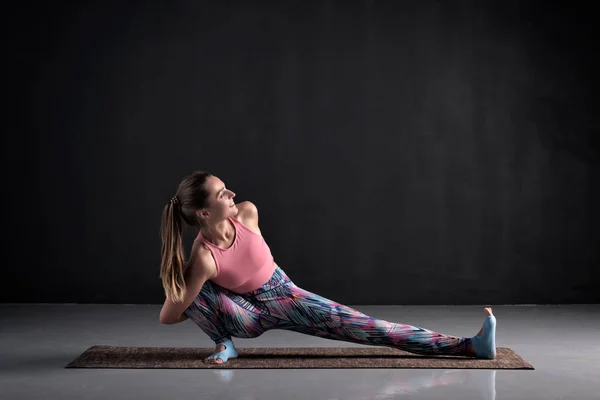 Hermosa mujer haciendo pose Skandasana en clase de yoga, Studio shot . — Foto de Stock