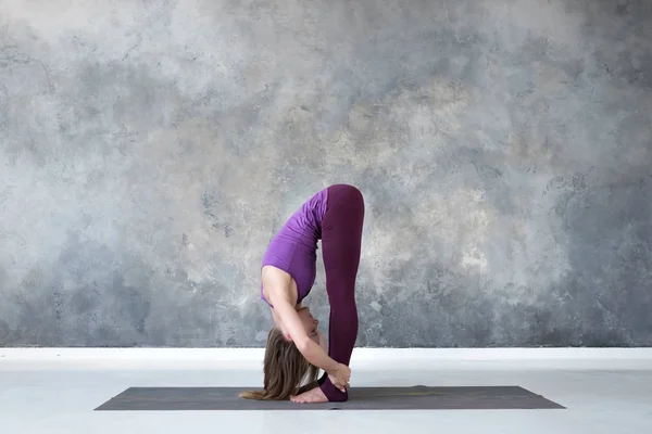 Vrouw doet hoofd naar de knieën, Uttanasana oefening, Standing Forward Bend pose — Stockfoto