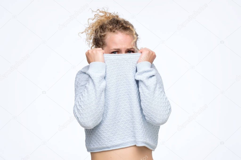 Caucasian girl with a social phobia hides her face in a sweater.