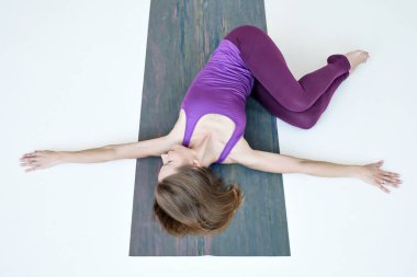 Belly Twist Pose'in zemin varyasyonu üzerine yoga egzersizi yapan kadın