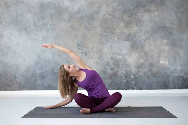 Jovem praticando ioga, sentado em pose de Sukhasana, exercício de curvatura lateral — Fotografia de Stock