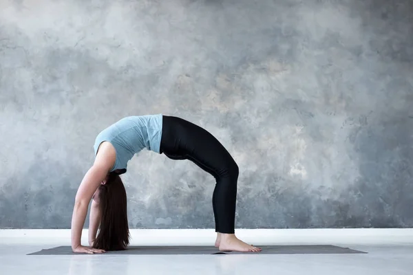 Vrouw beoefenen van yoga, staande in Urdhva Dhanurasana pose — Stockfoto