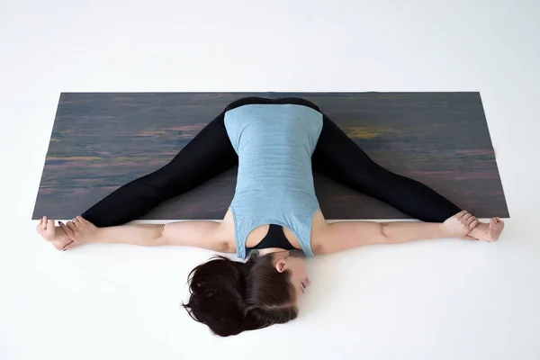 Caucasian woman doing yoga splits upavistha konasana on fitness mat. — Stock Photo, Image