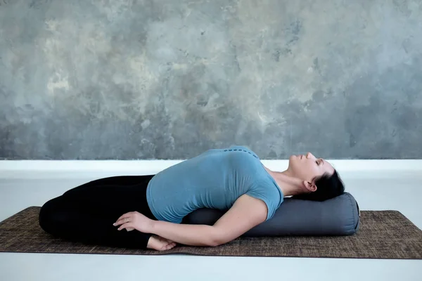 Cauacasian woman resting in reclining hero pose or Supta Virasana with bolster — Stock Photo, Image