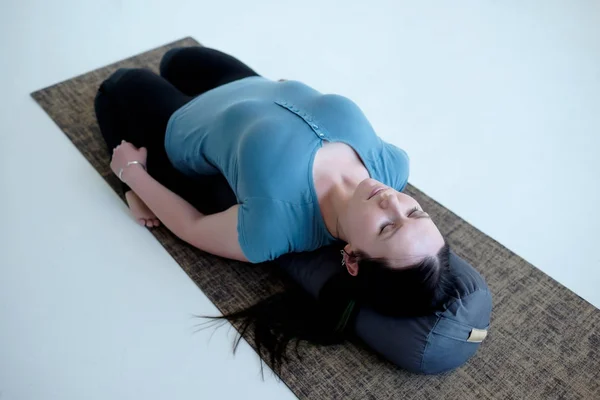 Cauacasian woman resting in reclining hero pose or Supta Virasana with bolster — Stock Photo, Image