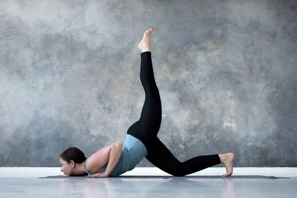 Vrouw beoefenen van yoga doen Eka Pada Shalabhasana, de sprinkhaan pose variatie — Stockfoto