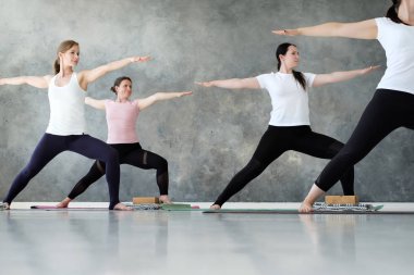 Genç sportif kadınlar Warrior İki egzersiz ayakta yoga dersi pratik