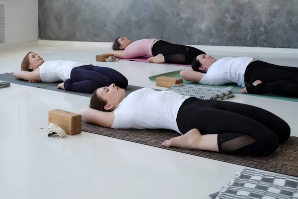 Young women doing yoga exercise, lying in Reclining Hero pose, Supta Virasana — Stock Photo, Image