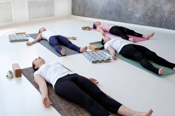 Women practicing yoga lesson, doing Dead Body, Savasana, exercise Corpse pose