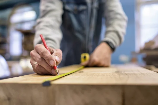 Línea de medición y trazado del carpintero con una regla y un lápiz sobre madera . — Foto de Stock