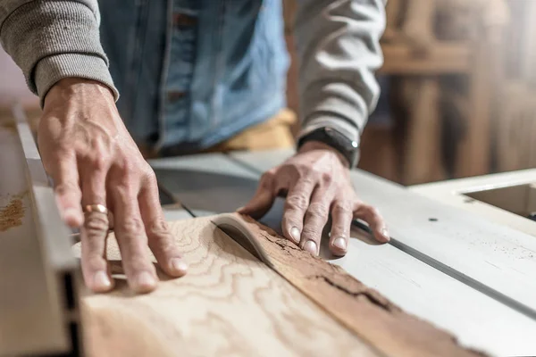 Sierra eléctrica cortando tabla de madera. Hombre trabajando en taller de carpintería — Foto de Stock