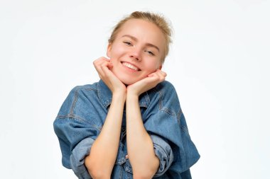 Sarı saçlı sevimli kız arkadaş geniş gülümseyen ve yumruklar üzerinde yüz eğilerek