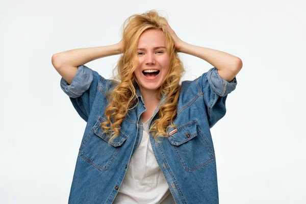 Kot pantolongüzel genç kadın, bağırarak, elleri baş tutuyor.