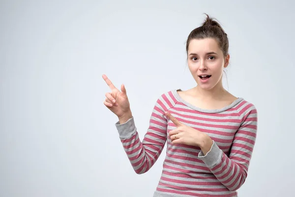 Donna sorridente ampiamente puntando le dita lontano, mostrando qualcosa di interessante — Foto Stock