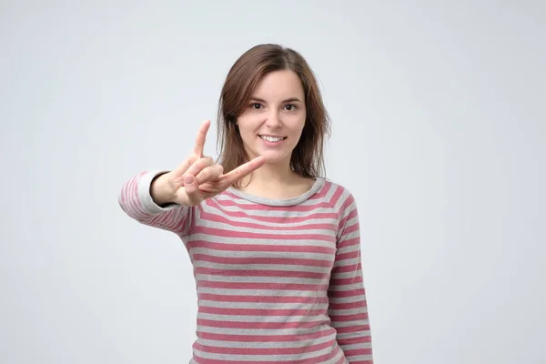 Jovem mulher europeia mostrando gesto de mão rock and roll posando em estúdio . — Fotografia de Stock