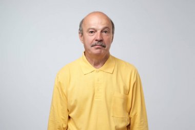 Üzgün üzgün olgun İspanyol adam sarı pullover suçluluk ve üzüntü ile bakıyor