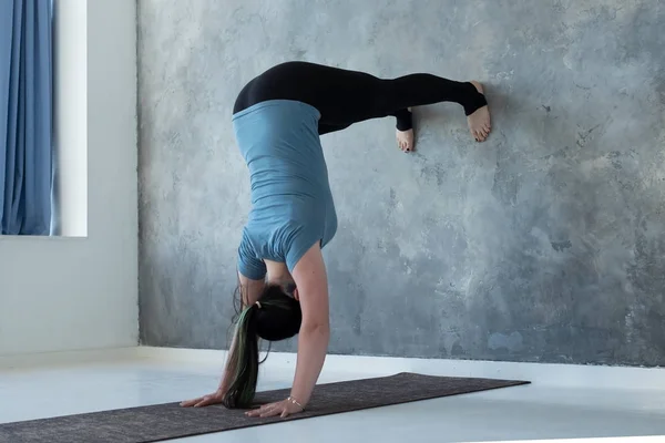 Woman learning to stand on hands near wall. Upside down yoga position — Stock Photo, Image