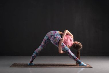 Genç kadın Trikonasana yoga poz varyasyon yapıyor