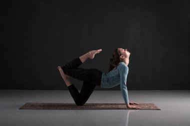 Genç kadın yoga yapıyor, egzersiz yapıyor. Kapalı tam uzunlukta
