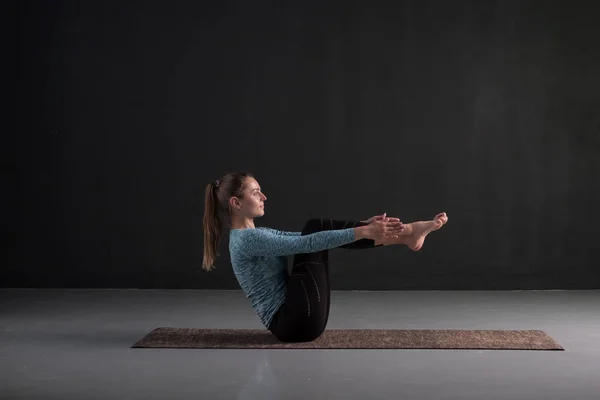 Kız yoga uygulamaları, tekne poz yapıyor, Navasana, abs için egzersiz. — Stok fotoğraf