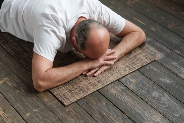 Hombre anciano mayor descansando después del ejercicio de yoga en el suelo. Deportes en casa para la salud . —  Fotos de Stock