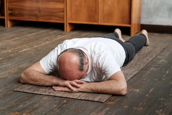 Senior äldre man vilar efter yoga övning på golvet. Sport hemma för hälsa. — Stockfoto