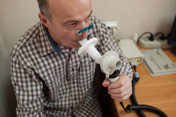 Hombre hispano mayor probando la función respiratoria por espirometría — Foto de Stock