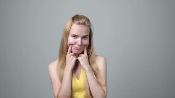 Jovem mulher fazendo falso sorriso com os dedos esticando os cantos de sua boca — Vídeo de Stock