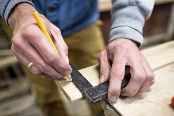 Carpenter using a straightedge to draw a line on a board — Stock Photo, Image