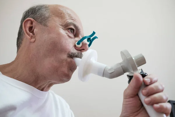 폐활량측정에 의한 호흡 기능을 테스트하는 수석 히스패닉 남자 — 스톡 사진