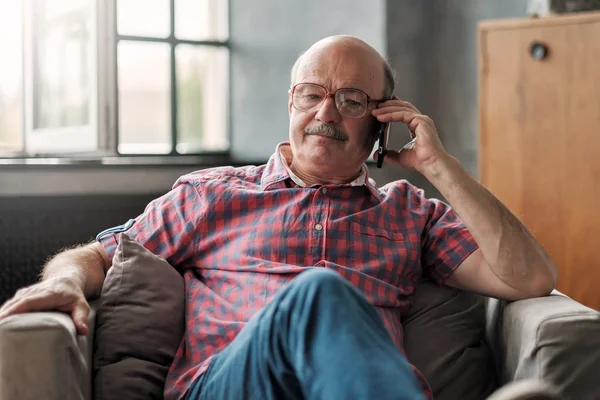 Вышедший на пенсию латиноамериканец говорит по телефону, сидя в гостиной . — стоковое фото