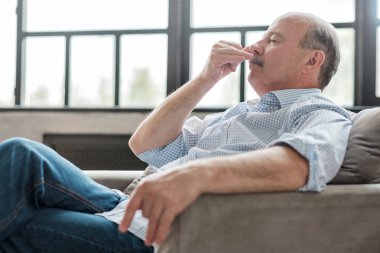 evde bir kanepede oturan adam nefes egzersizleri yapıyor